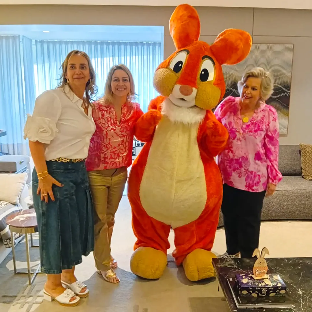 Criança pequena abraçando mascotinho de Coelho da Páscoa em cenário decorado de Páscoa.