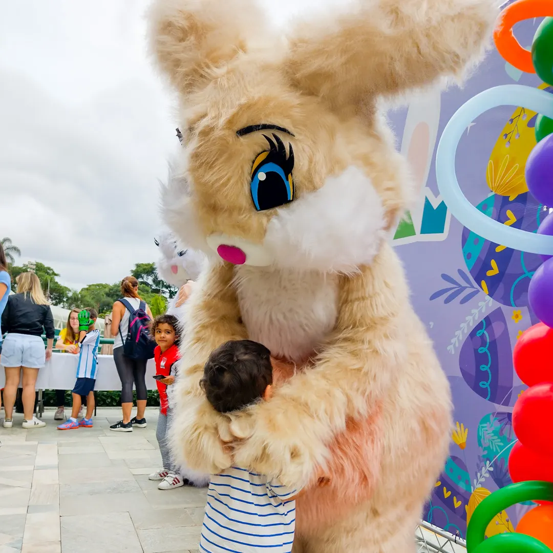 Crianças abraçando com alegria o Coelho Bege Peludo Personagem Vivo durante evento festivo em São Pa Crianças abraçando com alegria o Coelho Bege Peludo Personagem Vivo durante evento festivo em São Pa