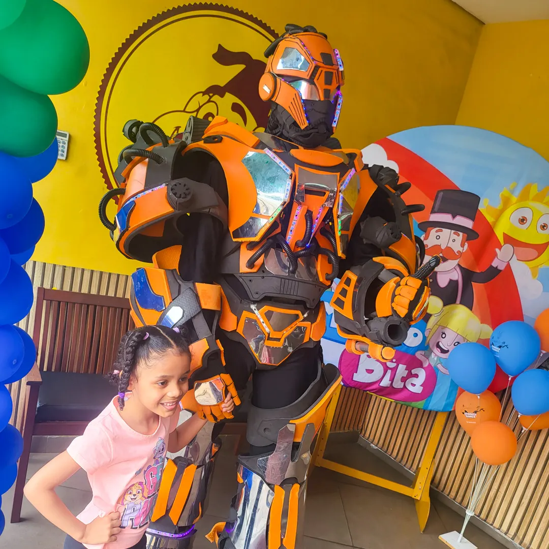 Crianças interagindo e tirando fotos com Robô Laranja Personagem Vivo no palco da festa Crianças interagindo e tirando fotos com Robô Laranja Personagem Vivo no palco da festa