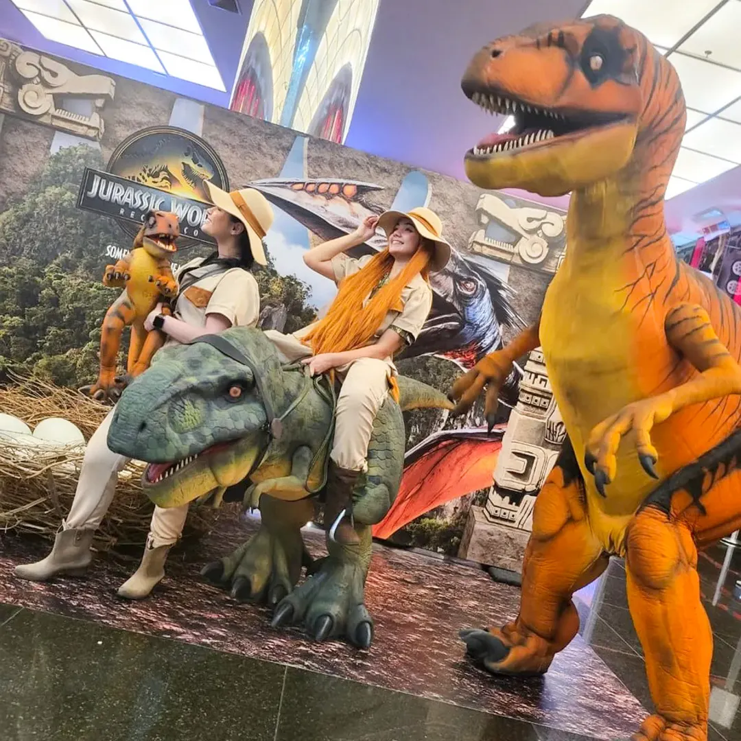 Família e convidados tirando foto ao lado da atração Dinossauros para Eventos em decoração temática jurássica.