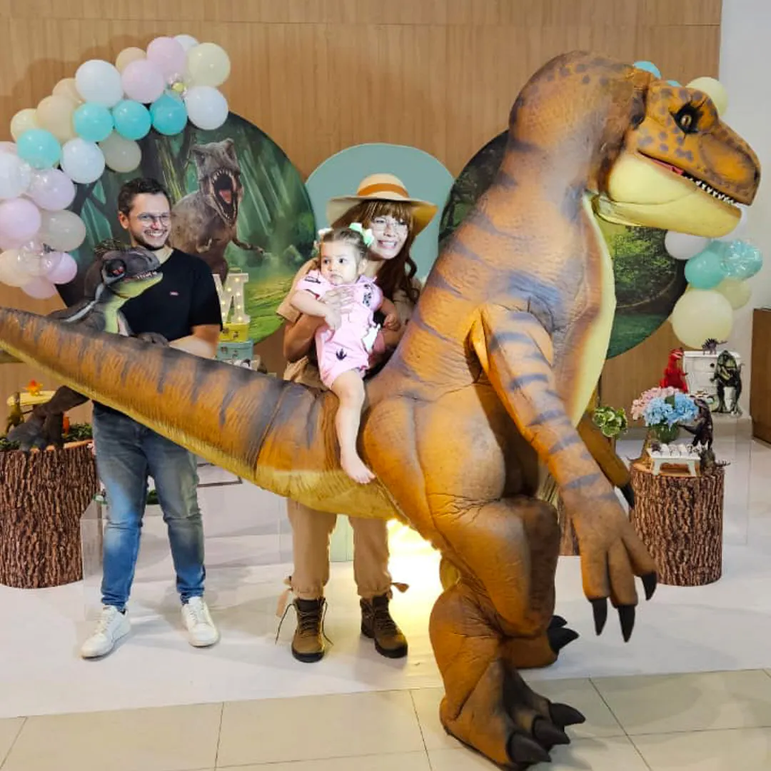 Família reunida comemorando o parabéns ao lado de T-Rex Laranja Personagem Vivo em SP
