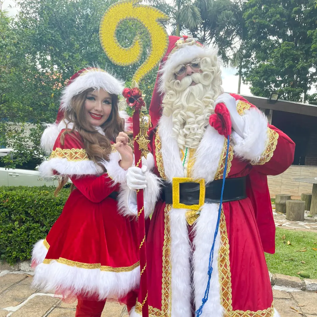 Papai Noel acompanhado da Mamãe Noel e duendes ajudantes em evento natalino de condomínio.