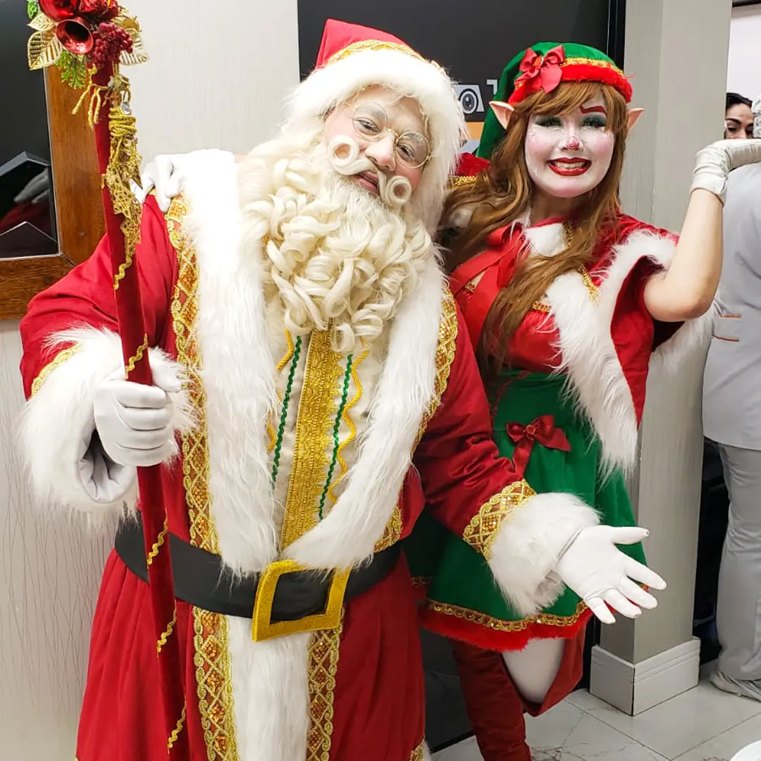 Papai Noel com barba natural e traje de veludo vermelho sorrindo em decoração natalina da empresa Feliz Natal.