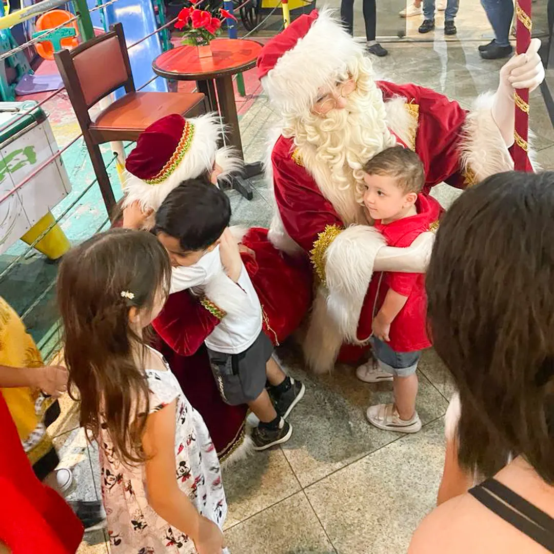 Papai Noel profissional entregando presente de Natal para criança em visita domiciliar na noite de Natal.
