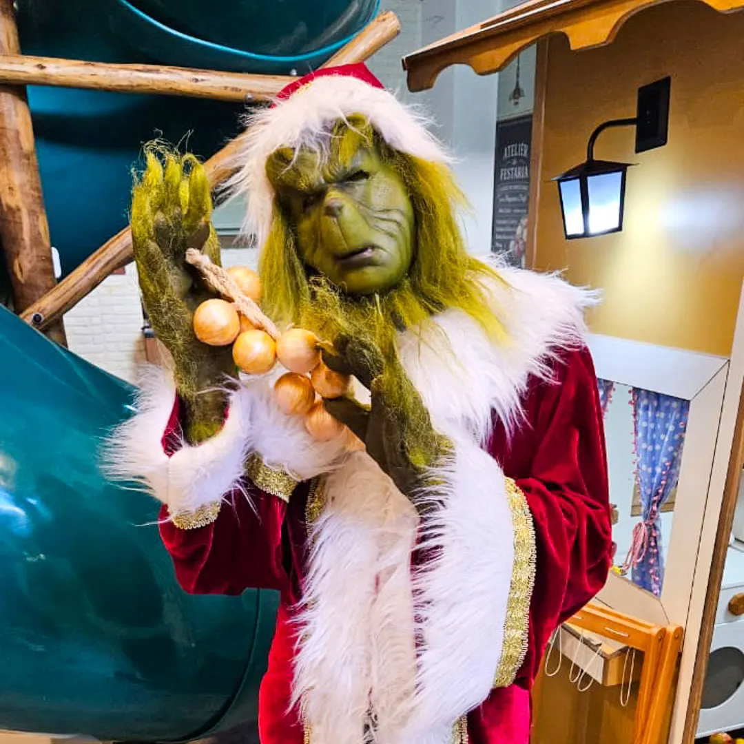Pose cômica do Grinch Personagem Vivo ao lado da decoração temática de aniversário